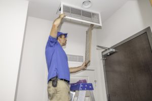 Technician on a ladder replacing a dirty air filter