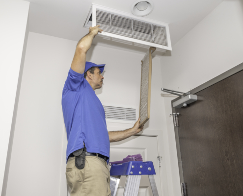 Technician on a ladder replacing a dirty air filter
