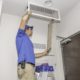 Technician on a ladder replacing a dirty air filter