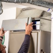 Man removes the furnace filter cover to inspect