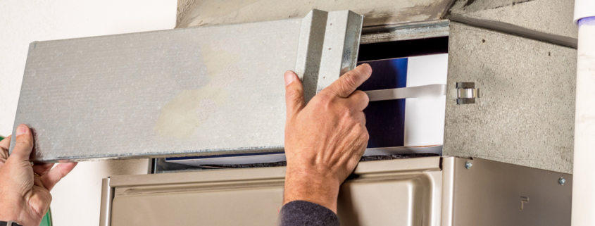 Man removes the furnace filter cover to inspect